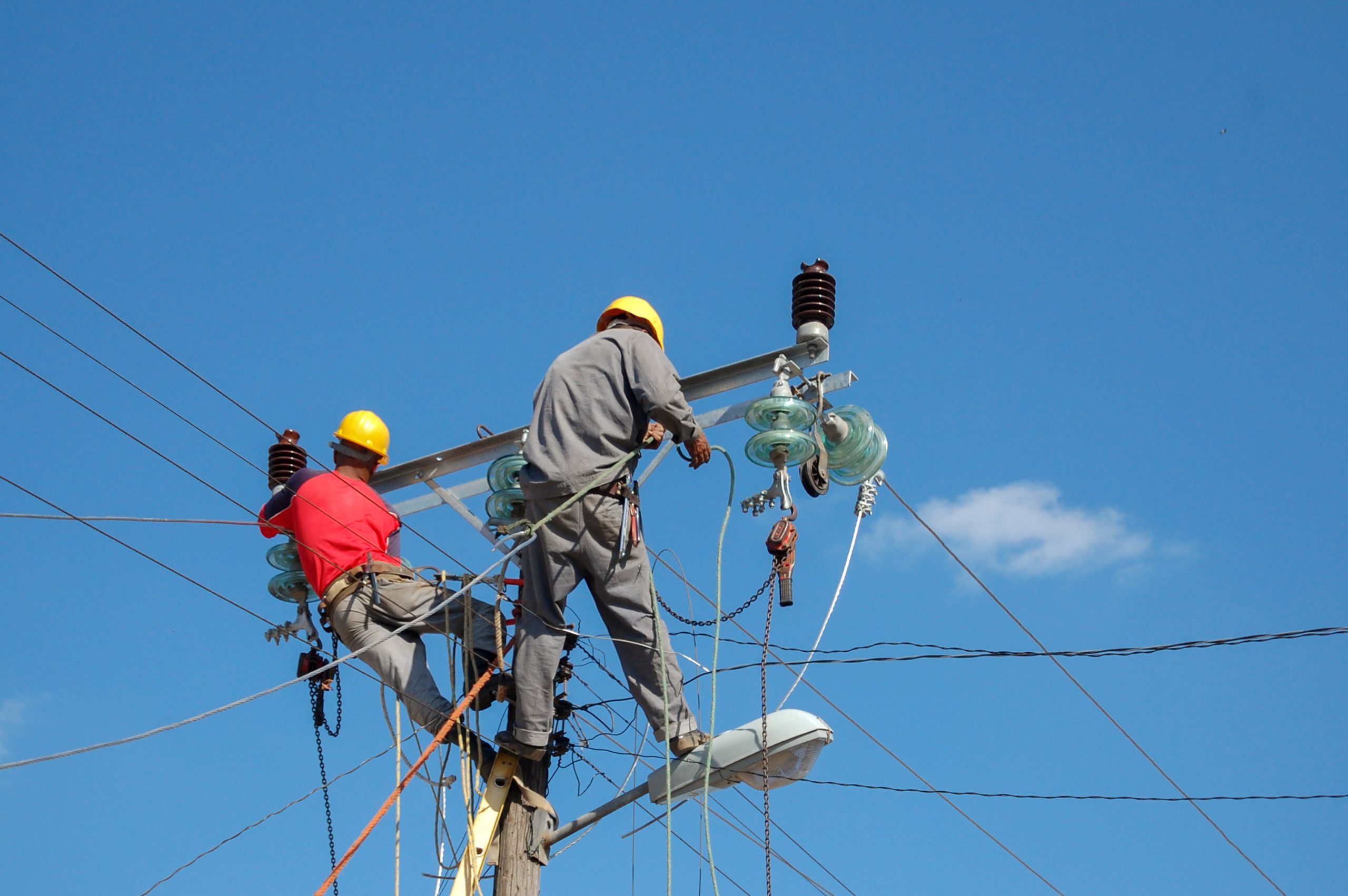 A low angle shot of electric linemen working on pole